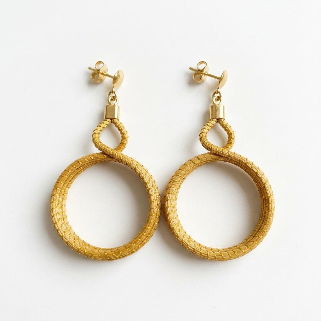 Boucles d'oreilles Cipó, anneaux entrelacés en or végétal du Brésil, capim dourado tressé à la main, vue trois quarts verticale