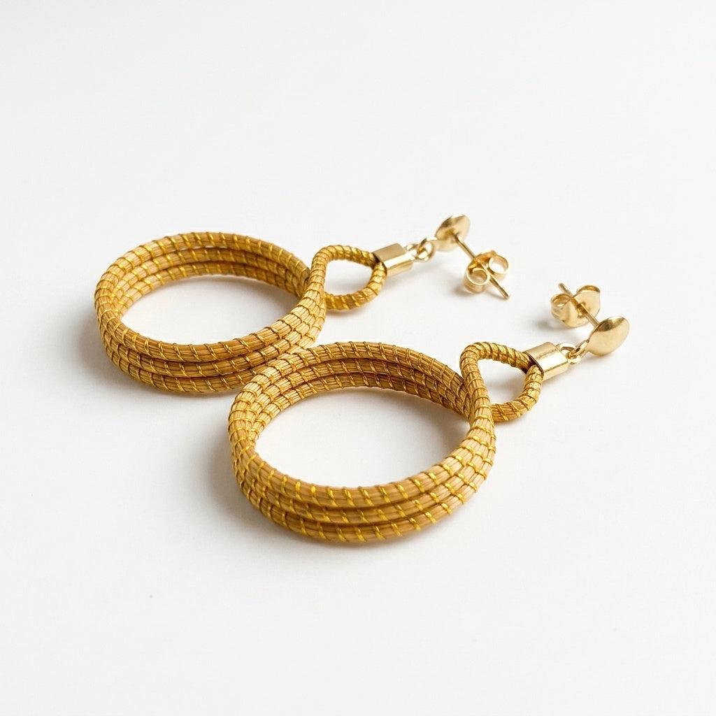 Boucles d'oreilles Cipó, bijou naturel fait main du Jalapão, anneaux entrelacés en fibre dorée, vue trois quarts ombrée
