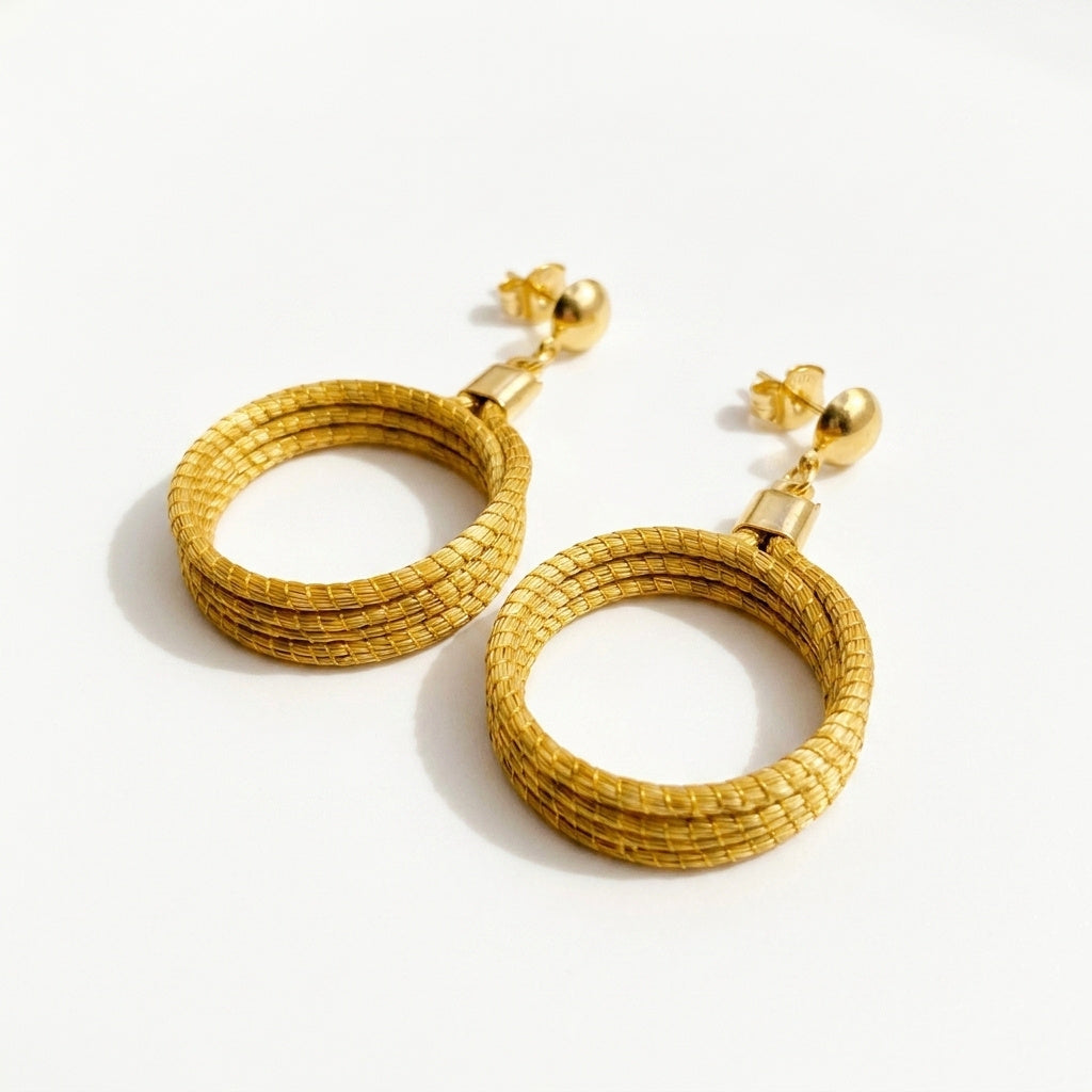 Boucles d'oreilles créoles en or végétal du Brésil, capim dourado tressé à la main, vue trois quarts verticale
