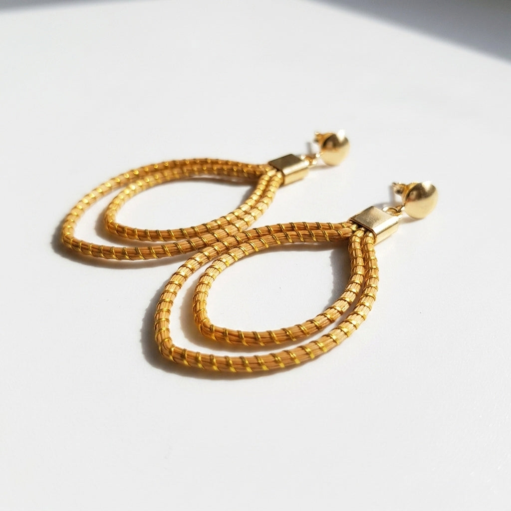 Boucles d'oreilles Curió, bijou artisanal naturel fait main au Tocantins, herbe dorée tressée, vue plat ombrée