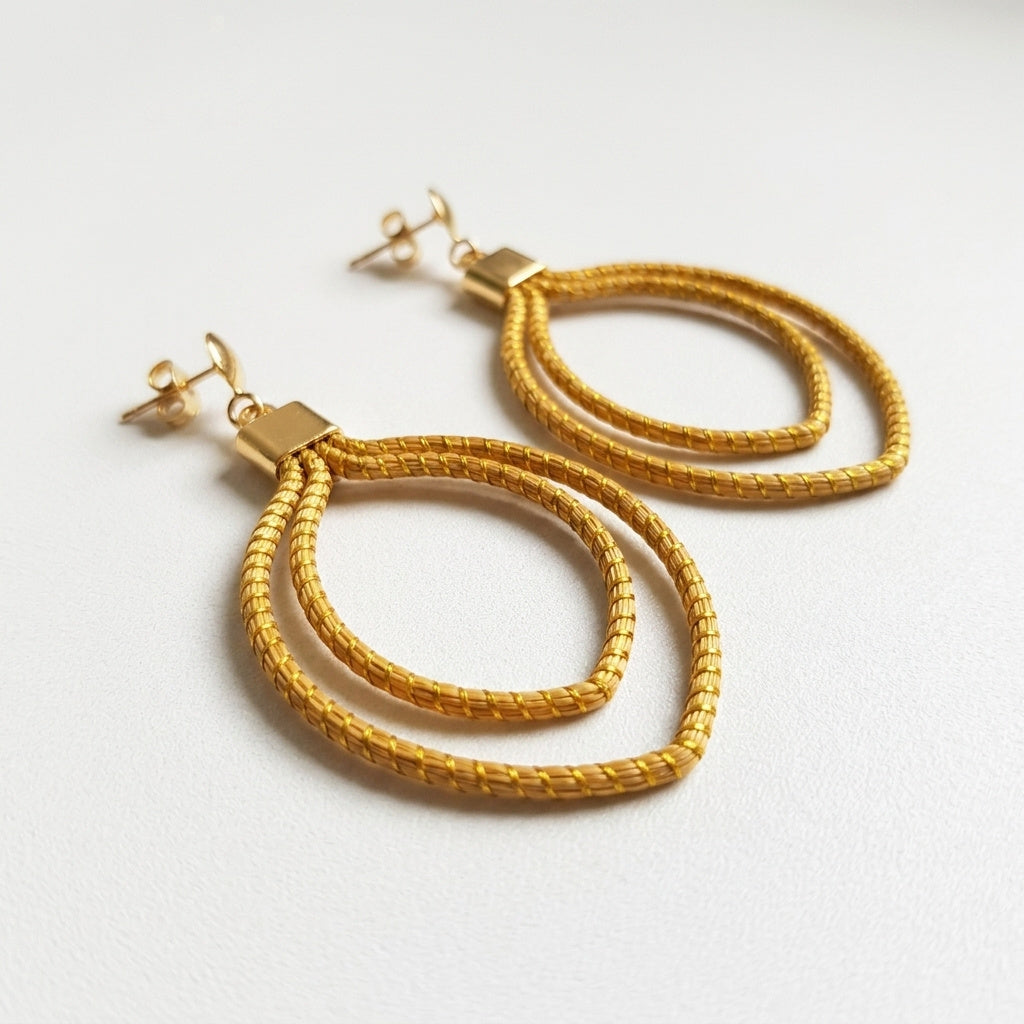Boucles d'oreilles Curió, feuille dorée en or végétal du Brésil, capim dourado tressé à la main, vue trois quarts verticale