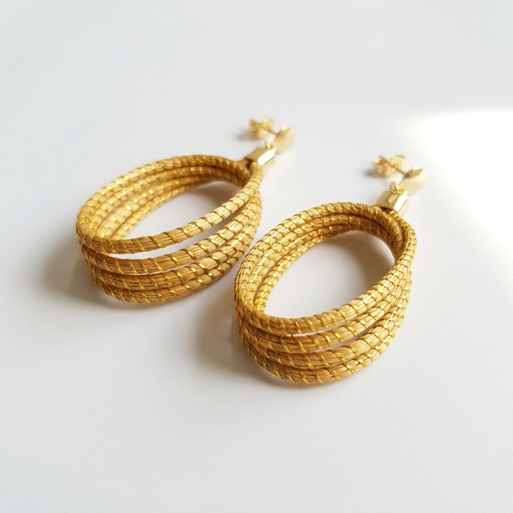 Boucles d'oreilles Guariba en fibre dorée du Jalapão, tressage main en capim dourado, vue trois quarts verticale