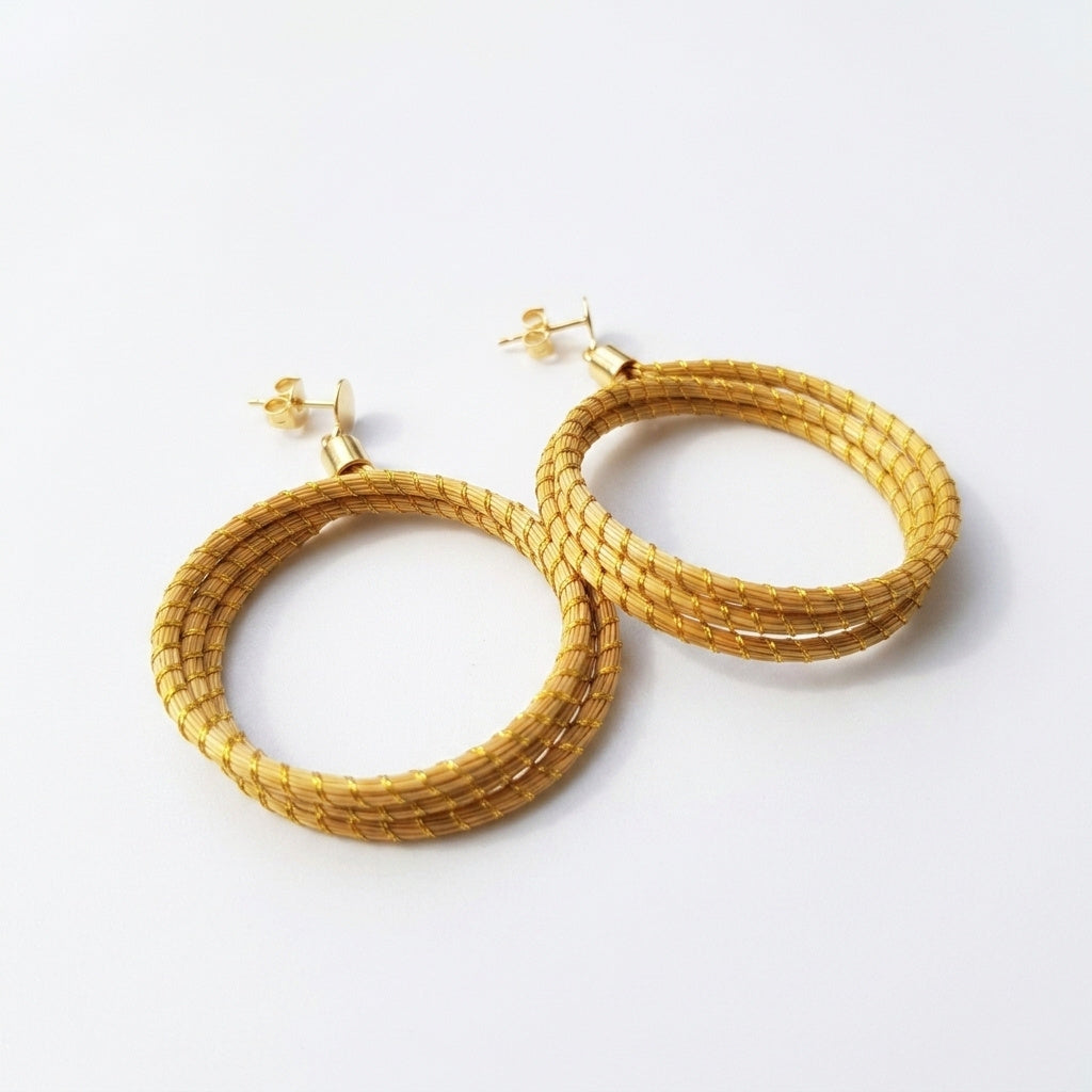 Boucles d'oreilles pendantes Icara dorées en or végétal du Brésil, double orbite en capim dourado, vue trois quarts