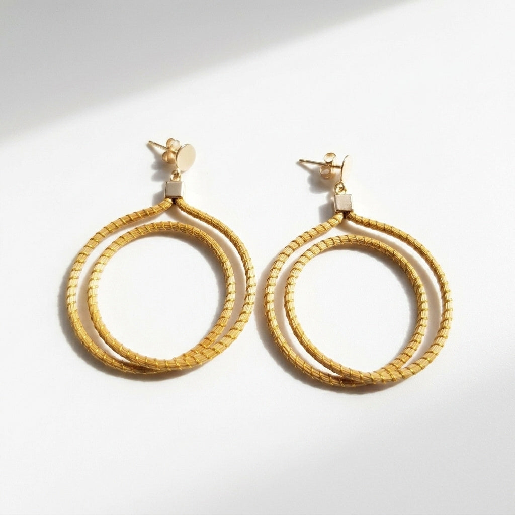 Boucles d'oreilles Jurema, créoles en or végétal du Brésil, fait main en capim dourado, vue trois quarts avec ombre douce