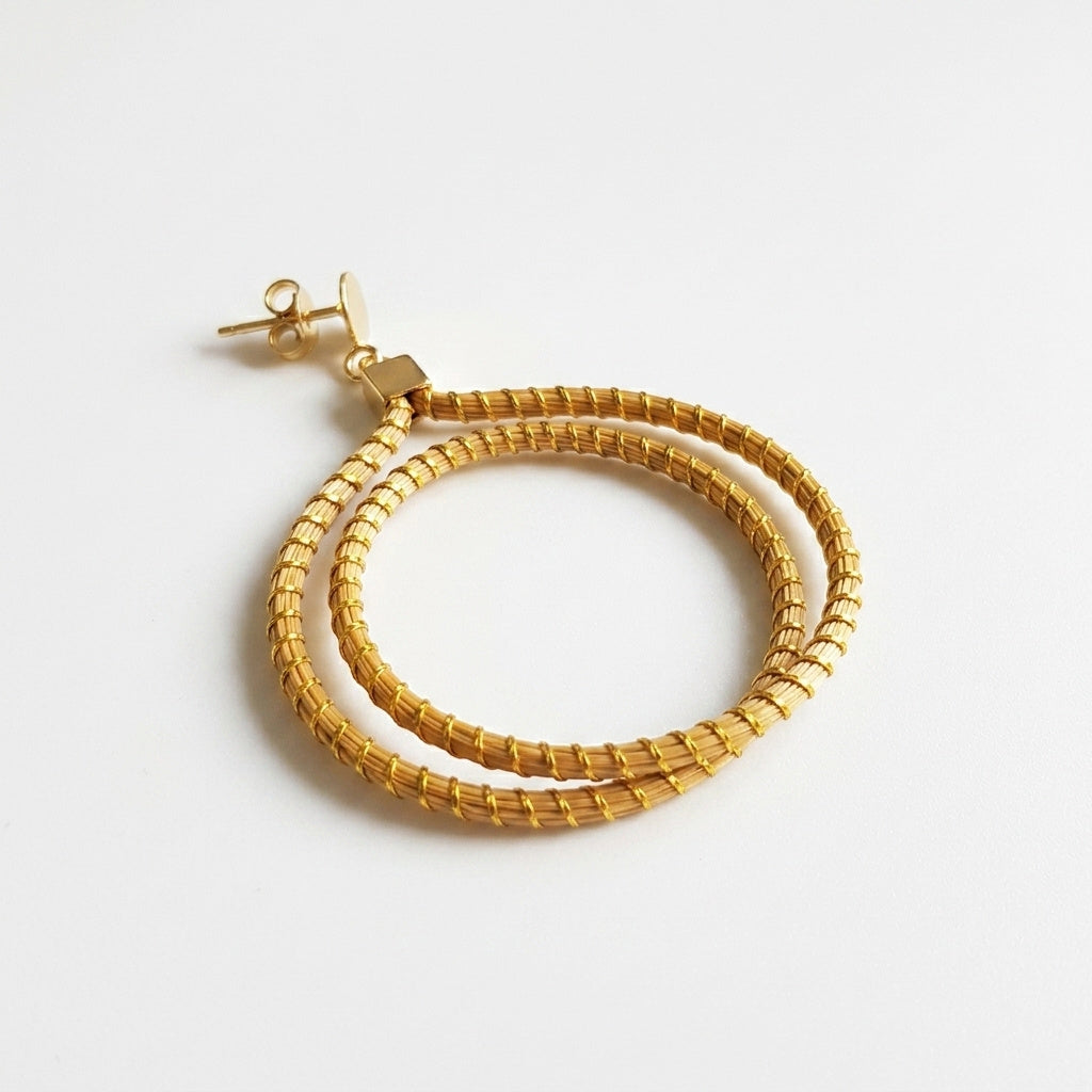 Boucles d'oreilles Jurema, détail d'une créole tressée en fibre dorée du Tocantins, vue à plat