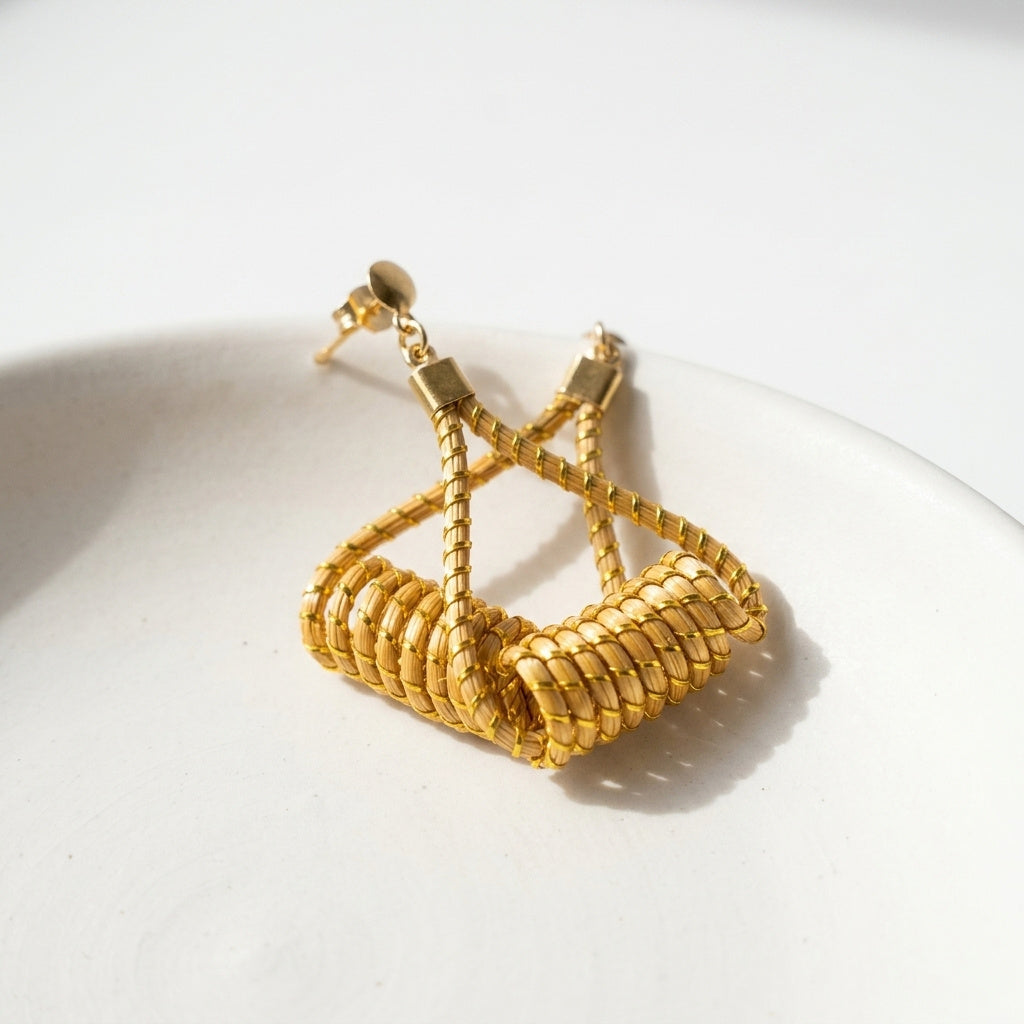 Boucles d'oreilles Matrinxá en fibre dorée tressée, présentation artistique sur céramique, vue en plongée