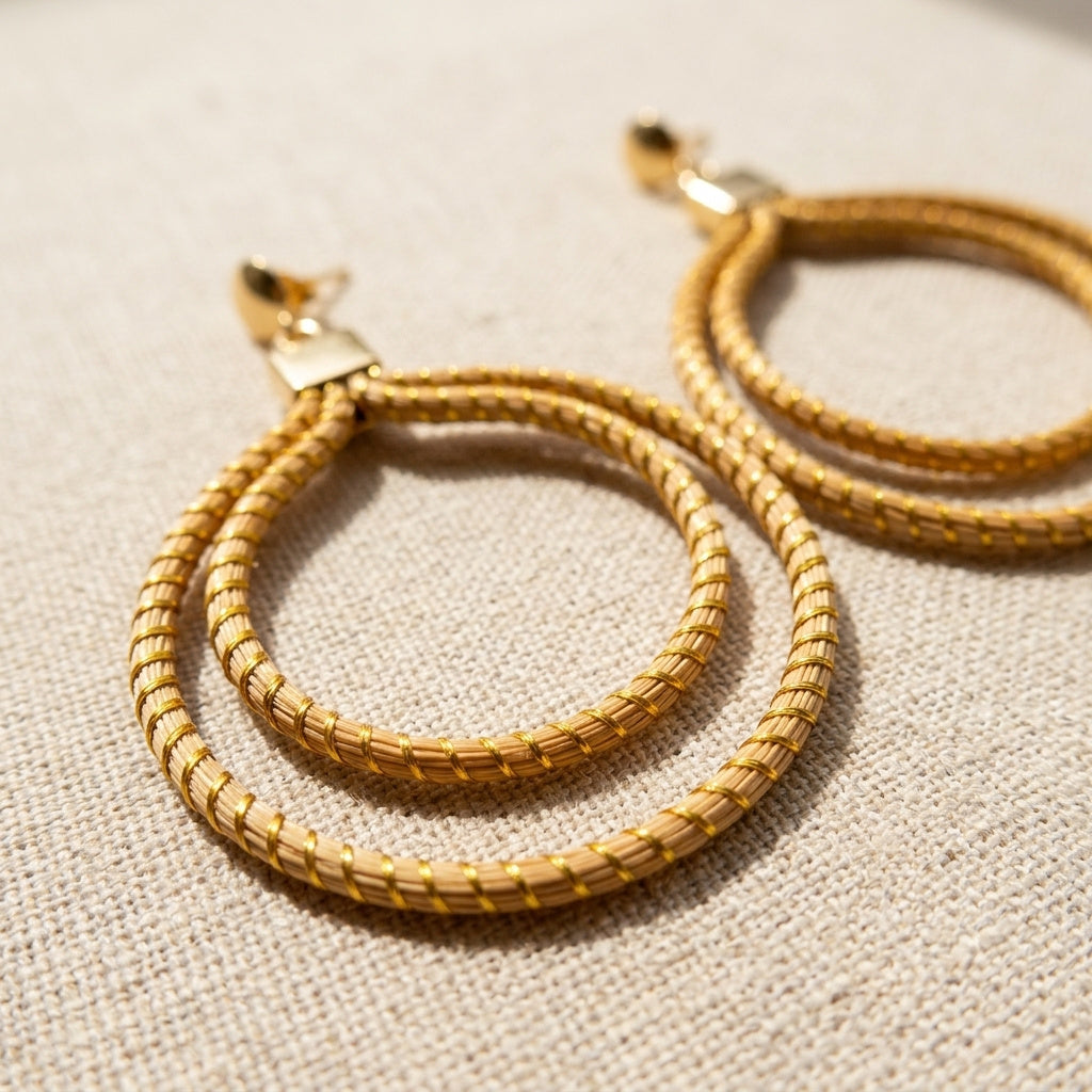 Boucles d'oreilles Nhambu, bijou artisanal naturel en herbe dorée, présentation sur tissu lin, gros plan double anneau