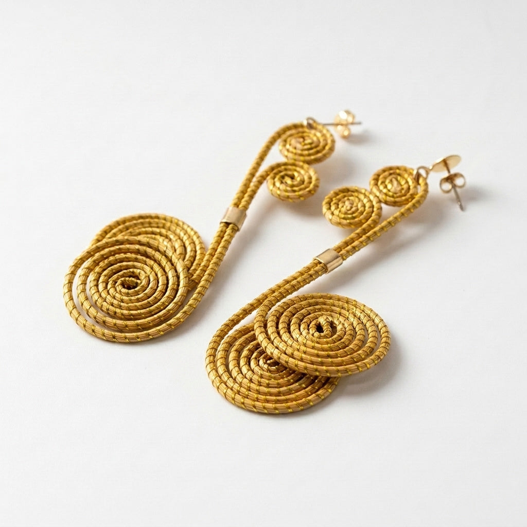 Boucles d'oreilles Tapajós, bijou végétal doré du Brésil, spirales enroulées vue trois quarts avec ombre douce