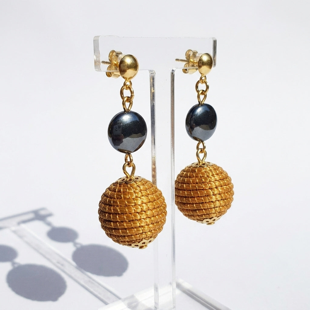 Boucles d'oreilles Taperá, bijou artisanal brésilien des artisans du Tocantins, sphère et perle hématite sur présentoir transparent