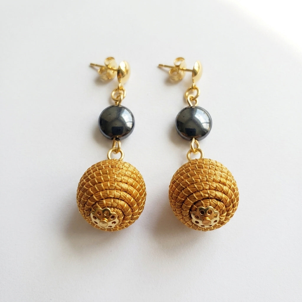 Boucles d'oreilles Taperá, sphère en or végétal du Brésil et perle hématite grise, capim dourado tressé à la main, vue frontale