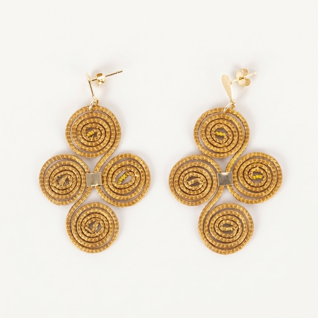 Boucles d'oreilles Cantão en capim dourado, motif croix de quatre spirales tressées en fibre dorée du Brésil, vue frontale sur fond blanc