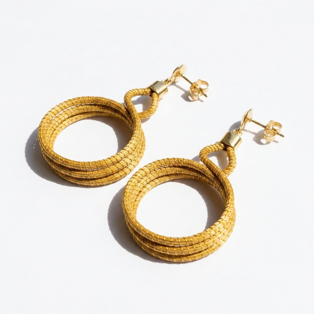 Boucles d'oreilles Cipó, bijou artisanal brésilien en herbe dorée, anneaux entrelacés vue trois quarts ouverte
