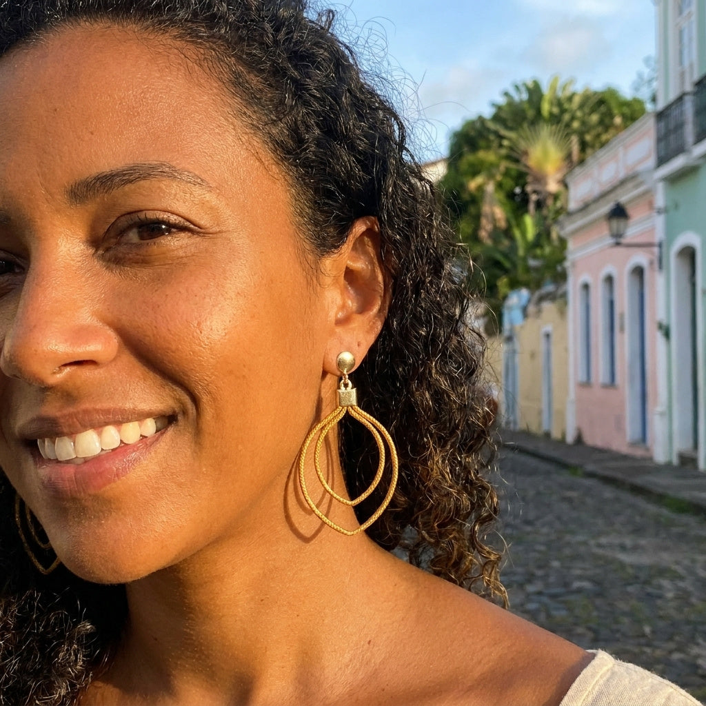 Boucles d'oreilles Curió en capim dourado portées par une femme dans une rue brésilienne, ambiance lifestyle urbaine