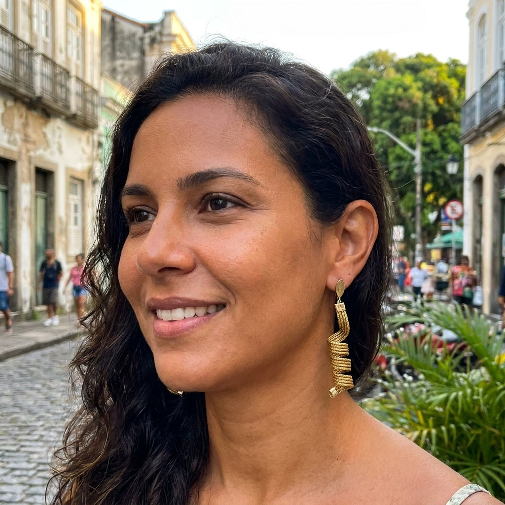 Boucles d'oreilles Guavira en capim dourado portées par une femme dans une rue brésilienne, ambiance urbaine