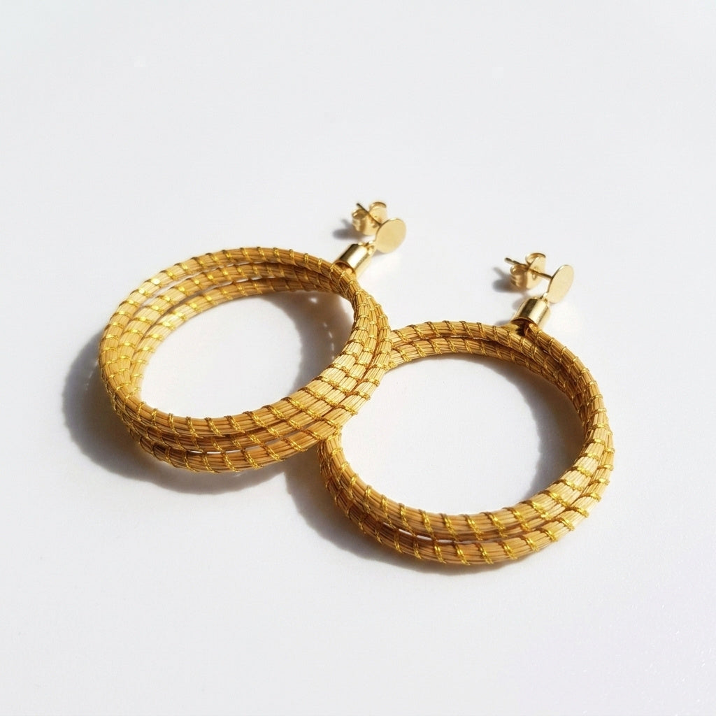 Boucles d'oreilles Icara, herbe dorée tressée du Jalapão, bijou naturel fait main, vue trois quarts à plat