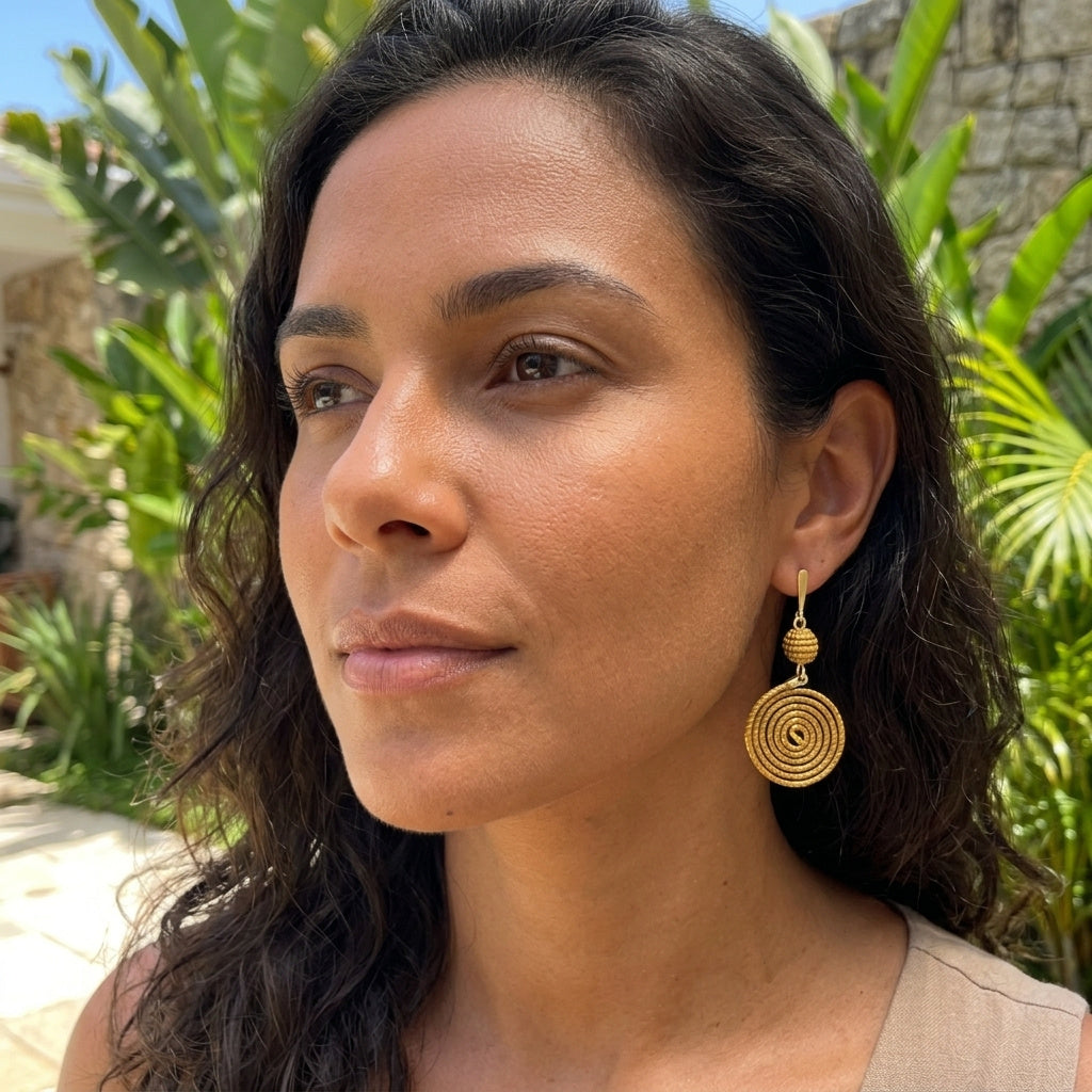 Boucles d'oreilles Manduri en capim dourado portées par une femme en extérieur au Brésil, ambiance tropicale