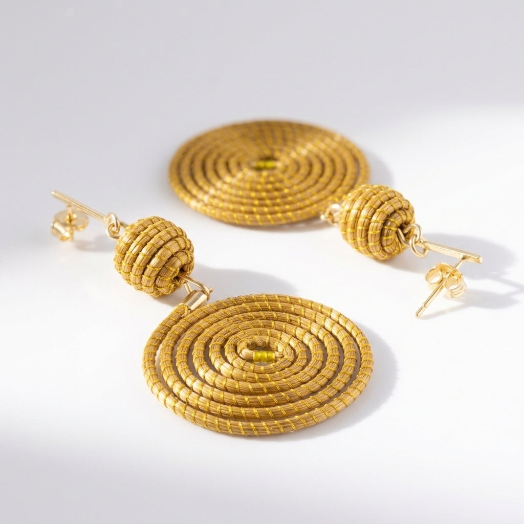 Boucles d'oreilles Manduri, spirales tressées en fibre dorée des artisans du Tocantins, vue trois quarts
