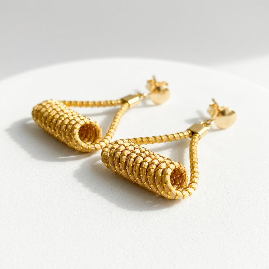 Boucles d'oreilles Matrinxá en capim dourado, disques empilés tressés en fibre dorée du Brésil, vue frontale architecturale