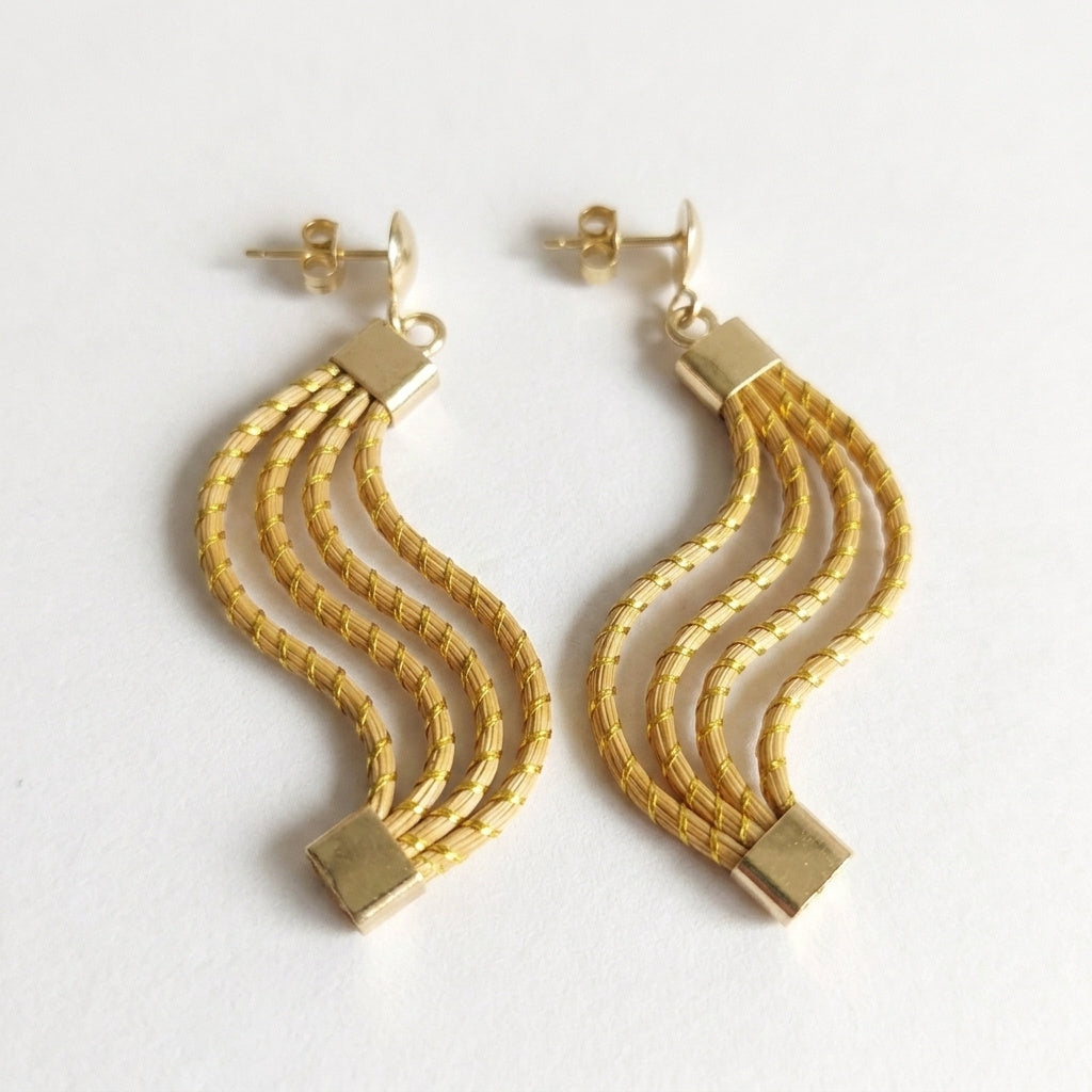 Boucles d'oreilles Taua en capim dourado, trois vagues ondulées tressées en fibre dorée du Brésil, vue frontale verticale