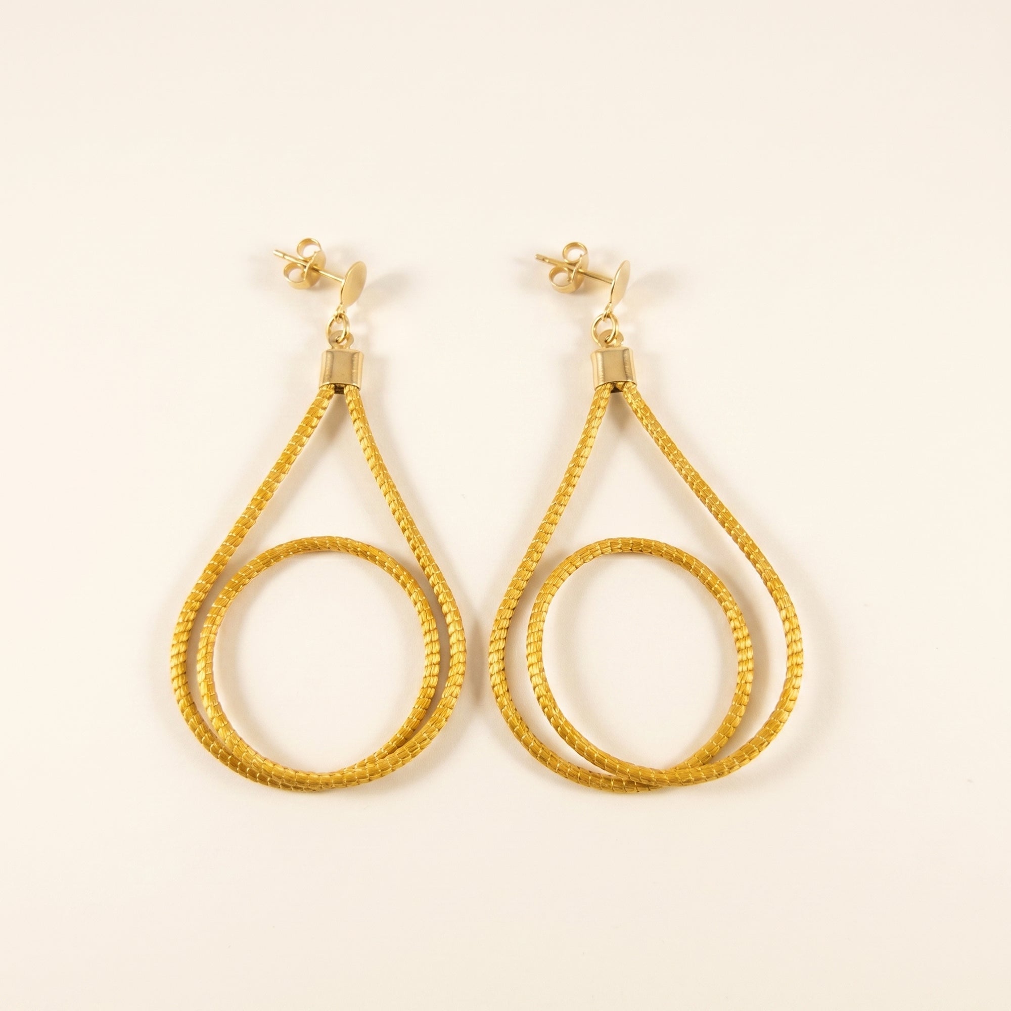 Boucles d'oreilles triangle cercle en capim dourado du Jalapão, fibre dorée tressée du Brésil, vue frontale sur fond clair