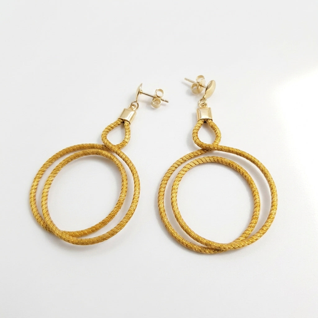 Boucles d'oreilles Urubu en capim dourado, double cercle tressé en fibre dorée du Brésil, vue frontale sur fond blanc